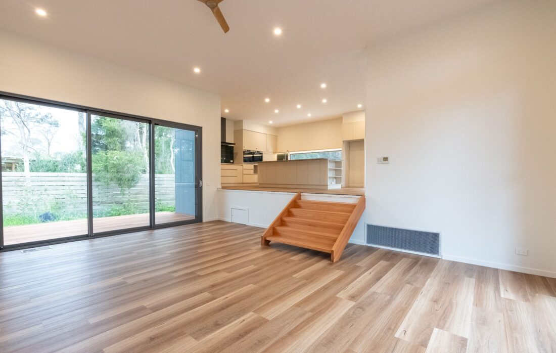 Living area with sliding doors and a timber stair up to the kitchen