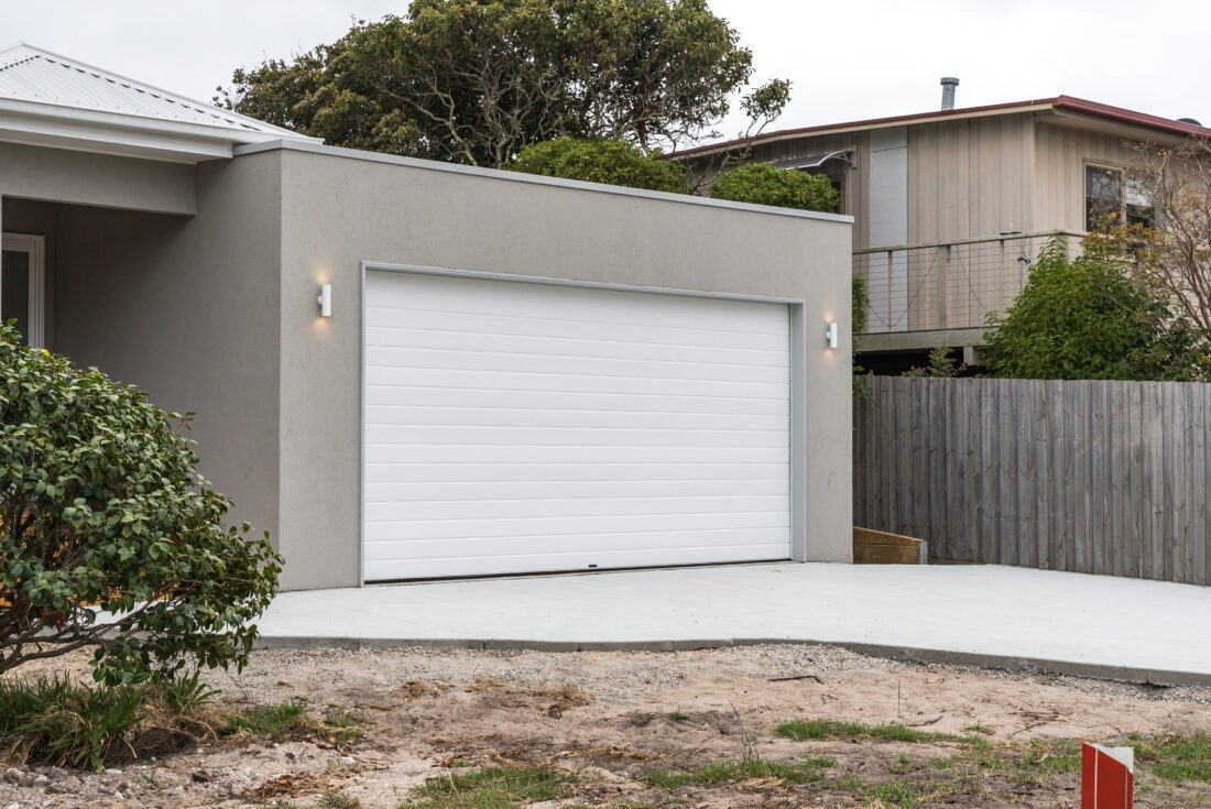 Rendered double garage with a white door and a concrete driveway