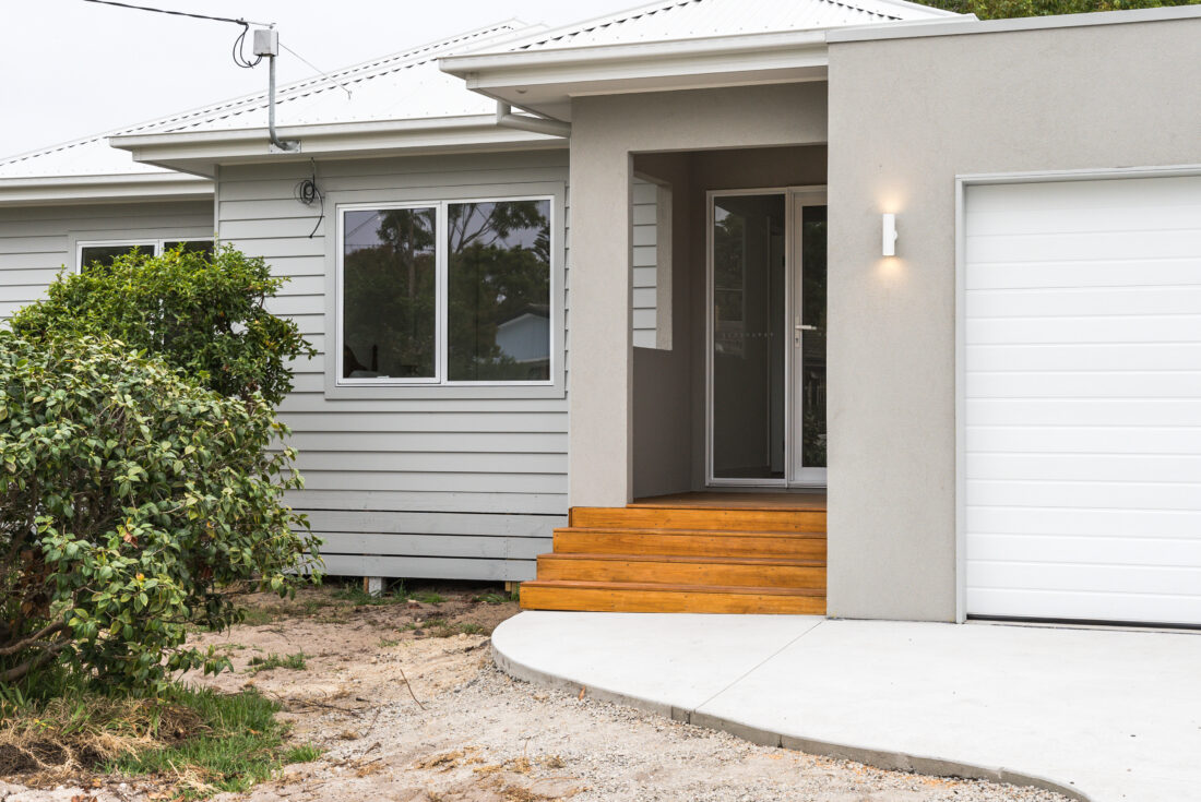 Entry with timber steps, grey cladding and a white garage door