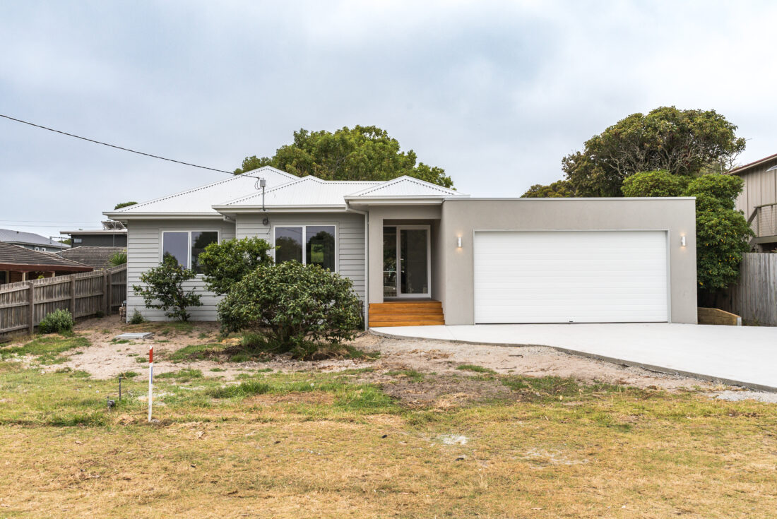 Single storey home with grey weatherboard cladding, a rendered garage and a timber entry stair