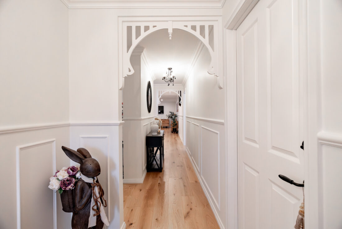 Hallway with a decorative timber arch, wall panelling and timber flooring