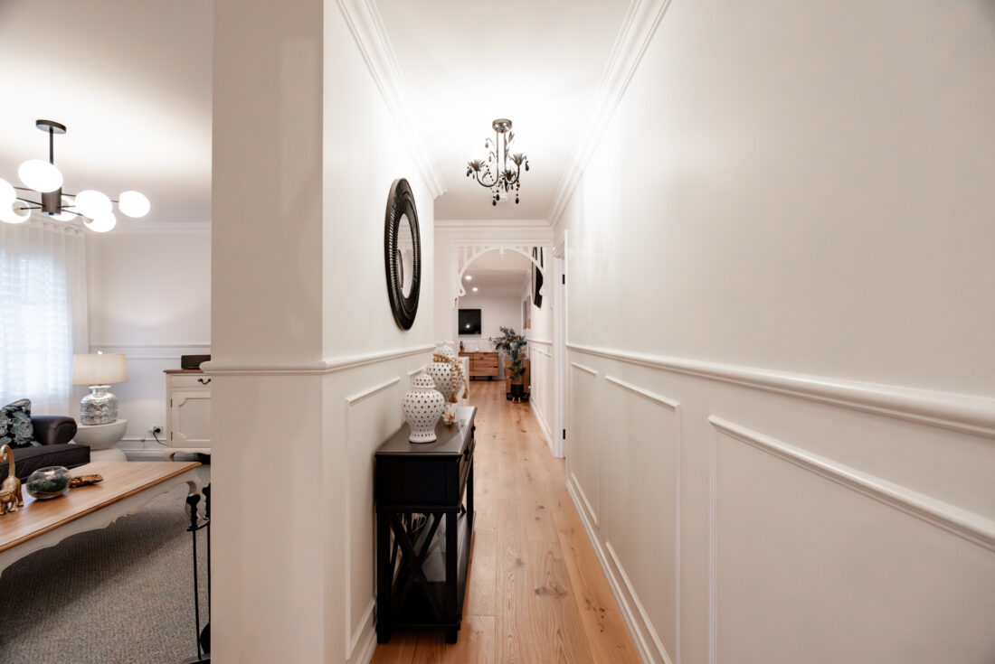 Hallway with wall panelling, a console table and timber floors