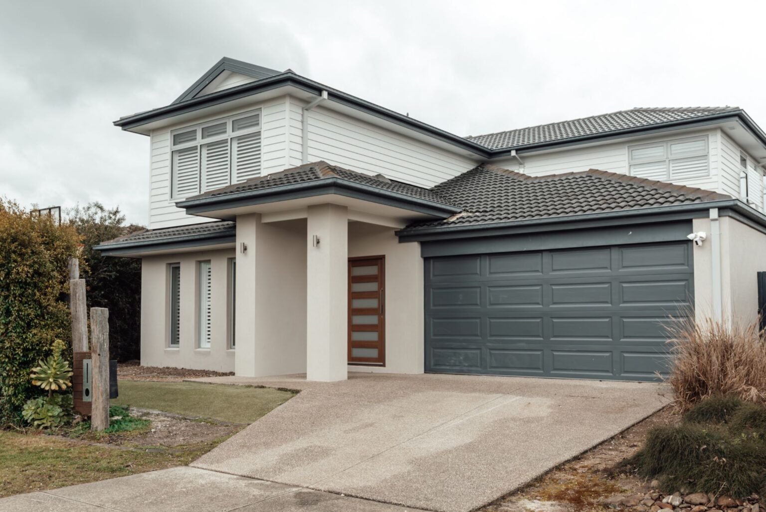 Two storey home with white cladding, a tiled roof and a double garage by Alberse Homes
