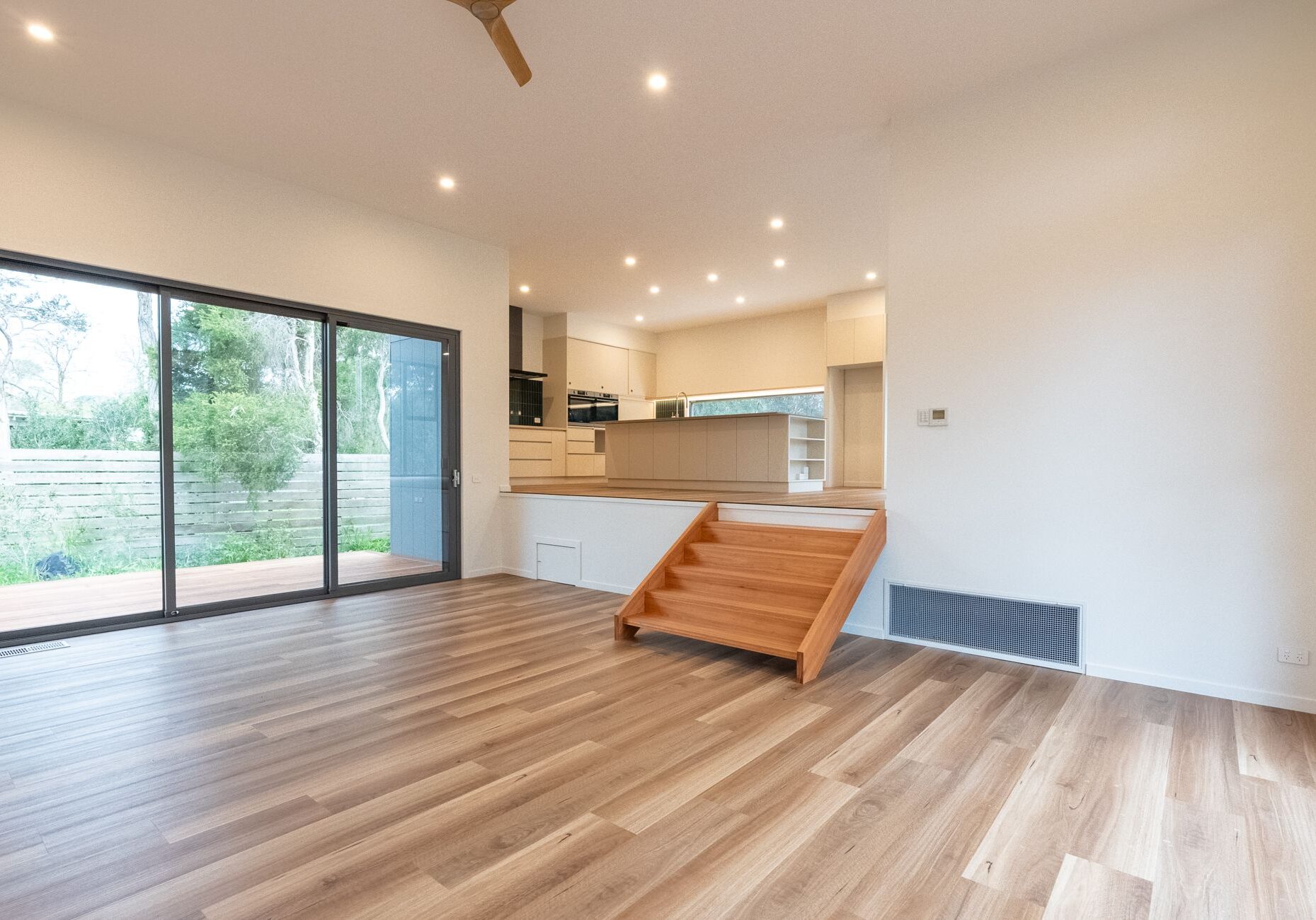 Living area with sliding doors and a timber stair up to the kitchen